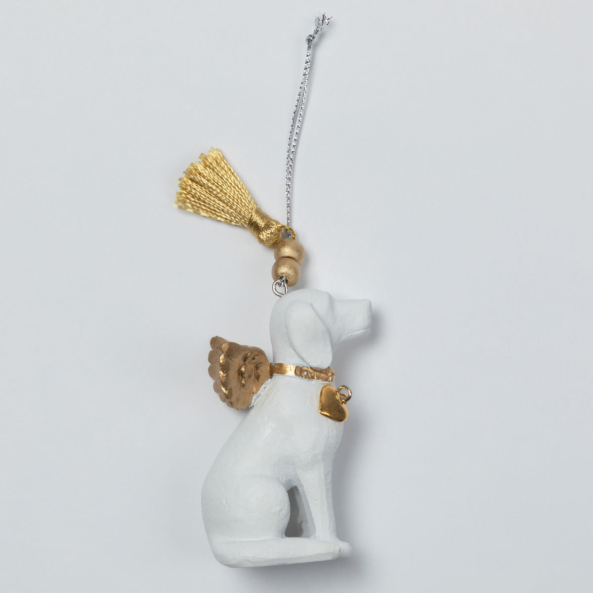 A white angel dog ornament with gold wings, collar, and tassel, hanging from a silver chain against a light gray background.
