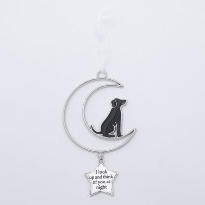 A silver crescent moon and dog Christmas ornament laying on a flat white surface.