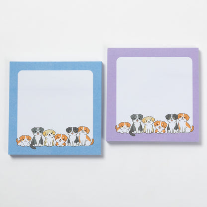 Two square sticky note pads with rounded corners on a white background. The left pad has a light blue border and the right pad has a lavender purple border, both featuring a row of cute illustrated dogs along the bottom edge.