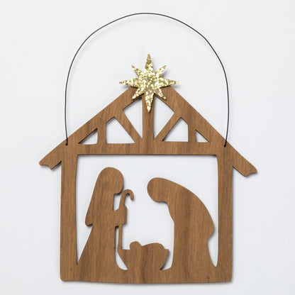 A wooden Nativity scene ornament with a star on top, shown on a plain light background.