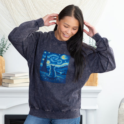 A woman wearing a dark gray acid-wash sweatshirt with a blue and yellow 'Starry Night' cat graphic, standing in front of a white fireplace mantel.