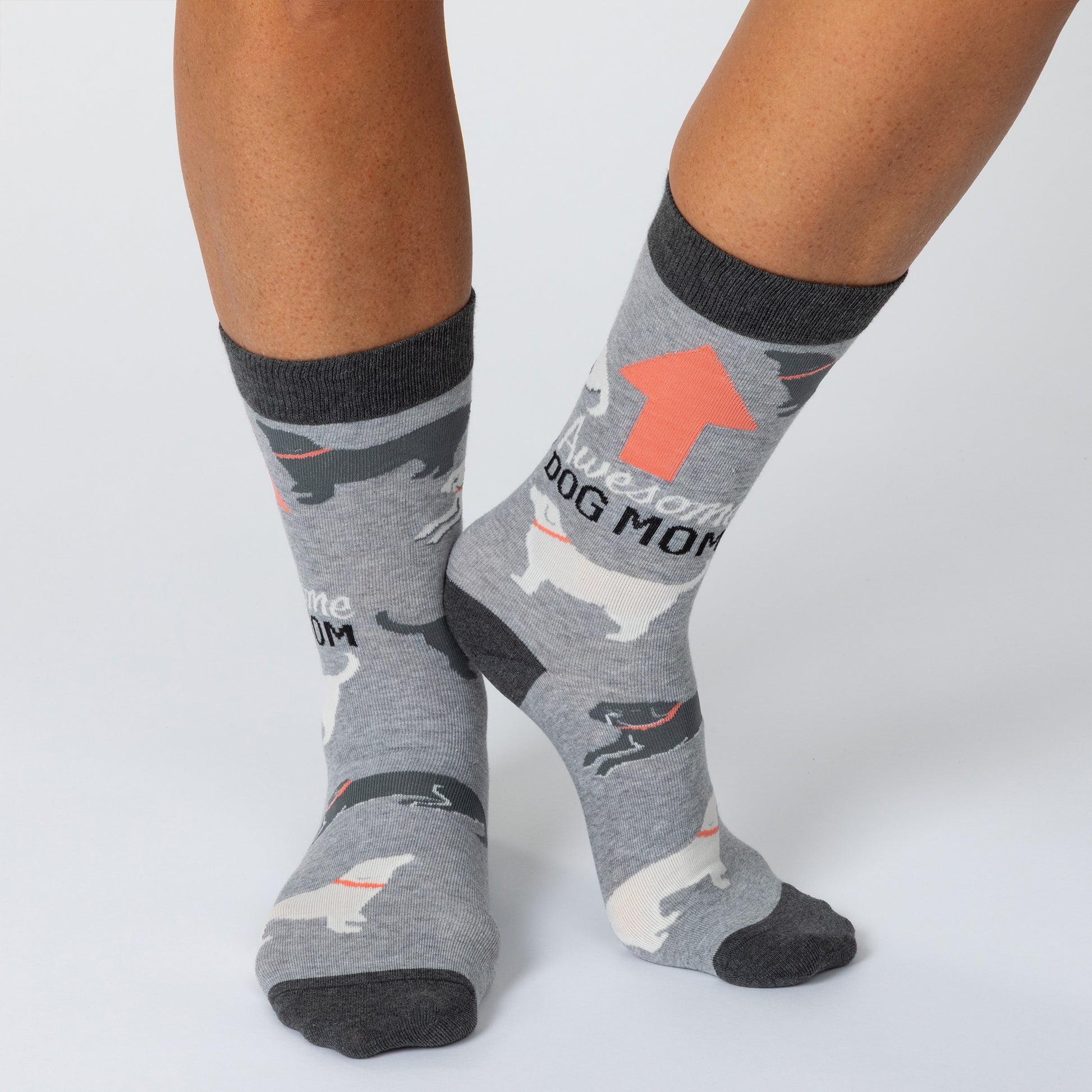 Feet wearing gray socks with dogs all over and the phrase "Awesome dog mom" with an arrow pointing up.