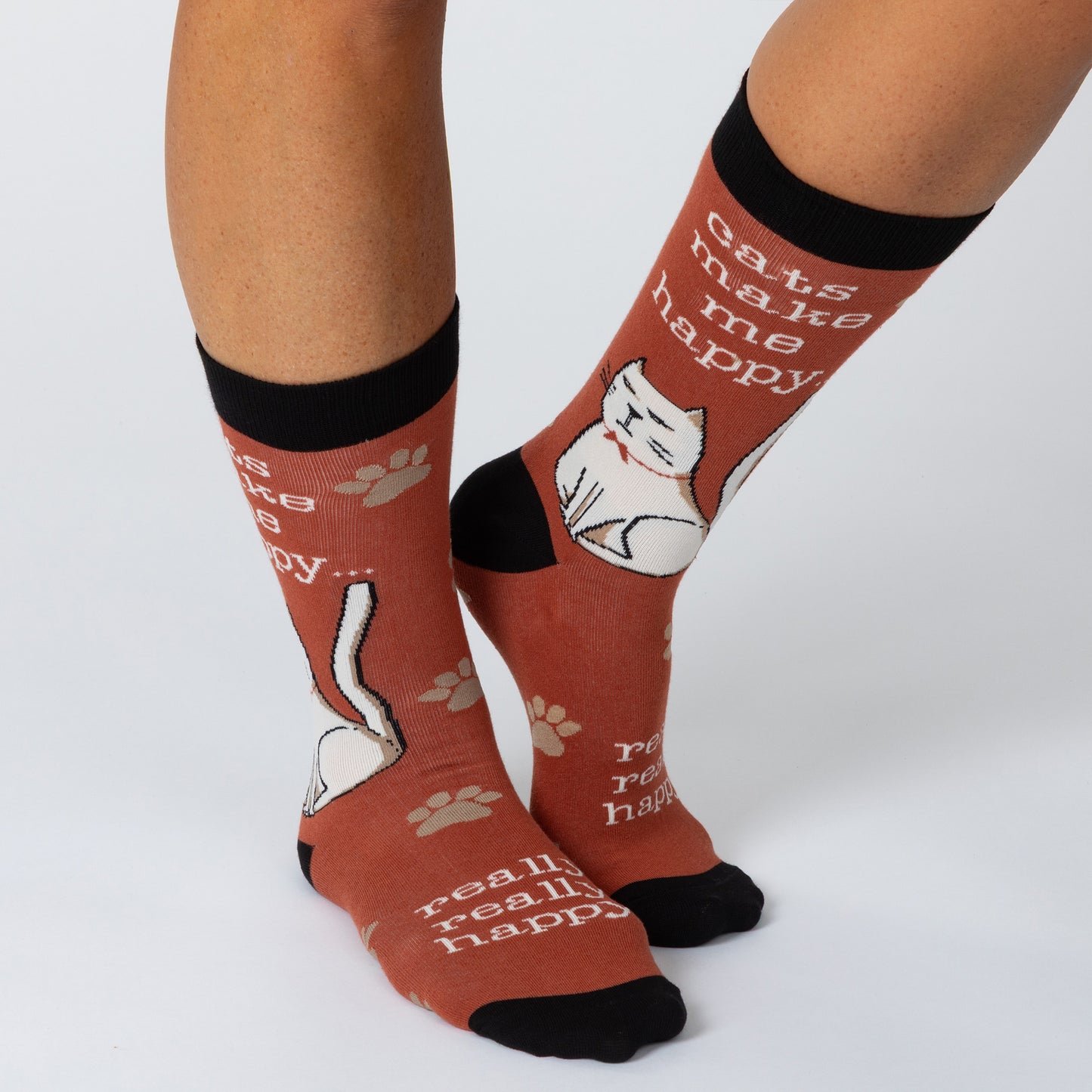 Feet wearing dark red socks with a cat surrounded by paws and the phrase "cats make me happy" and "really really happy."