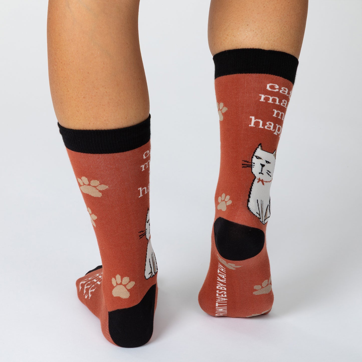Feet wearing dark red socks with a cat surrounded by paws and the phrase "cats make me happy" and "really really happy."
