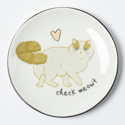 A round white ceramic plate with a black rim, featuring a hand-drawn illustration of a white cat with green-tinted eyes and a gold-tinted tail, a small beige heart above, and the text 'check meowt' below.