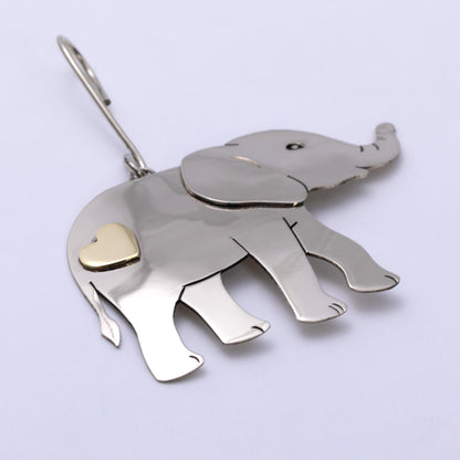 A silver elephant-shaped ornament with a small gold heart accent on its side, shown on a plain light background.