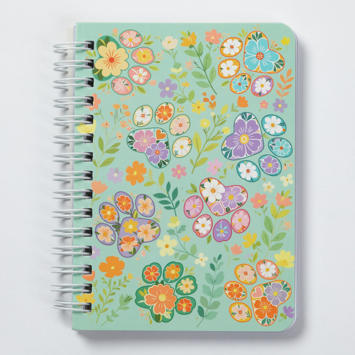 A spiral-bound notebook with a mint green cover decorated with a colorful floral pattern, shown on a light gray background.