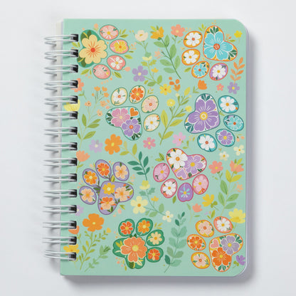 A spiral-bound notebook with a mint green cover decorated with a colorful floral pattern, shown on a light gray background.
