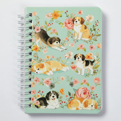 A spiral-bound notebook with a mint green cover decorated with watercolor illustrations of beagle dogs and pink, orange, and yellow flowers, shown on a light gray background.