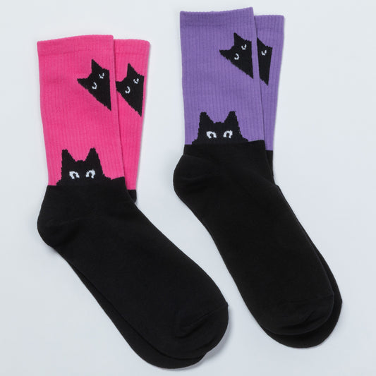 Two pairs of crew socks on a light gray background. One pair is bright pink with a black cat head pattern near the cuff, and the other pair is lavender purple with the same black cat head pattern.