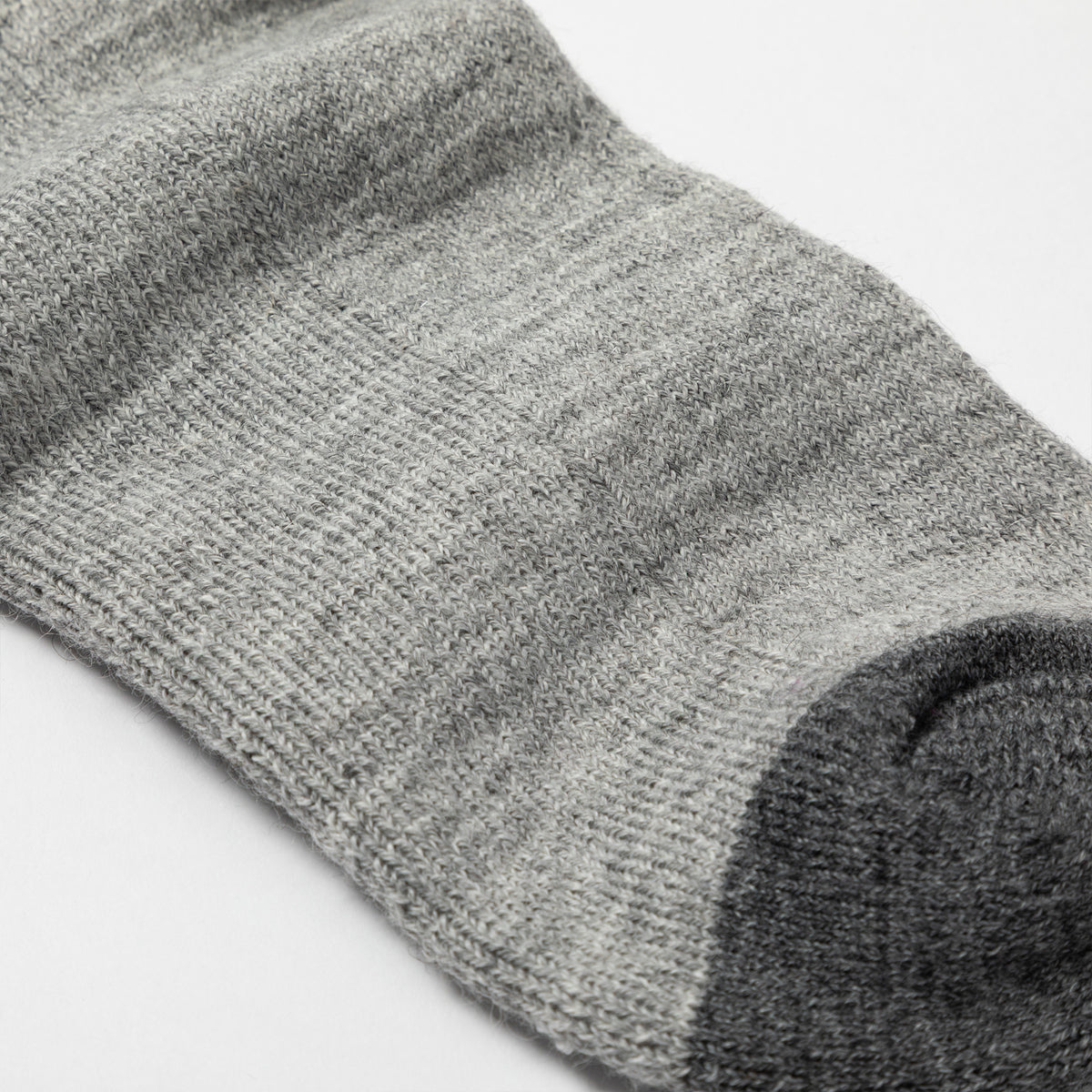 Close-up of a heather gray knit sock with a darker charcoal gray toe section, shown on a plain white background.