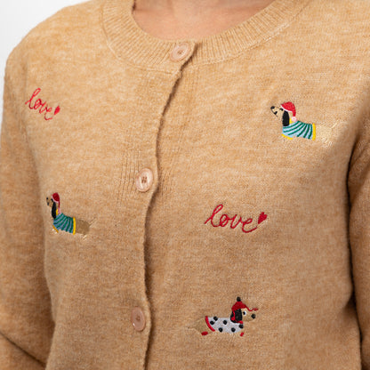 Close-up of a beige knit cardigan sweater with pink embroidered 'love' text and small colorful dachshund motifs on the front.