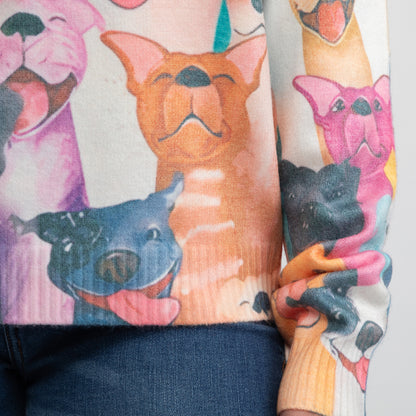A close-up of a person wearing a cream-colored knit sweater with a colorful cartoon dog print, paired with dark blue jeans.
