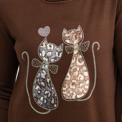 A close-up of a brown long-sleeve top featuring a graphic of two stylized cats with leopard and cheetah patterns, embellished with rhinestones, on a solid brown background.