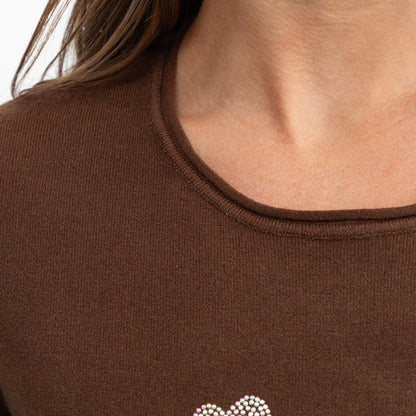 Close-up of a person wearing a brown ribbed knit top with a small rhinestone-embellished heart at the lower chest.