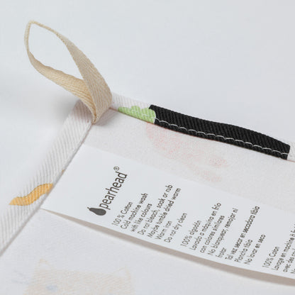 Close-up of a white Pearhead cotton dish towel with a beige hanging loop, a black stitched trim, and a printed care label.