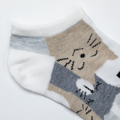 A close-up of a low-cut knit sock featuring a stylized cat face and body pattern in beige, gray, and white.