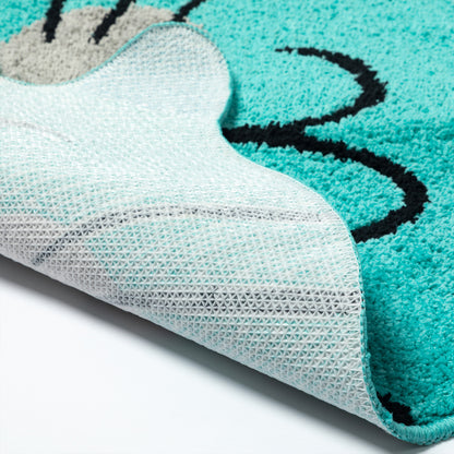Close-up of a plush rug with a turquoise and white cat-face design, showing the textured pile and the white backing.