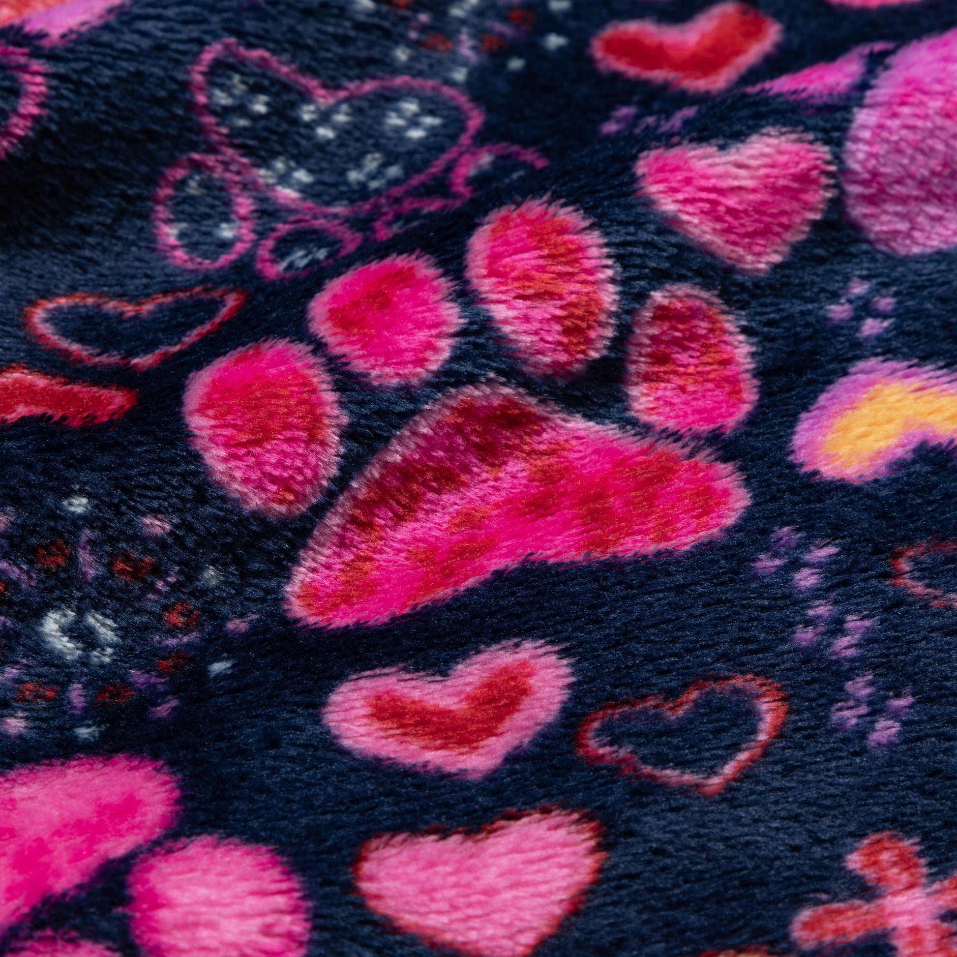 Close-up of fabric with pink hearts and paw print patterns on a dark background