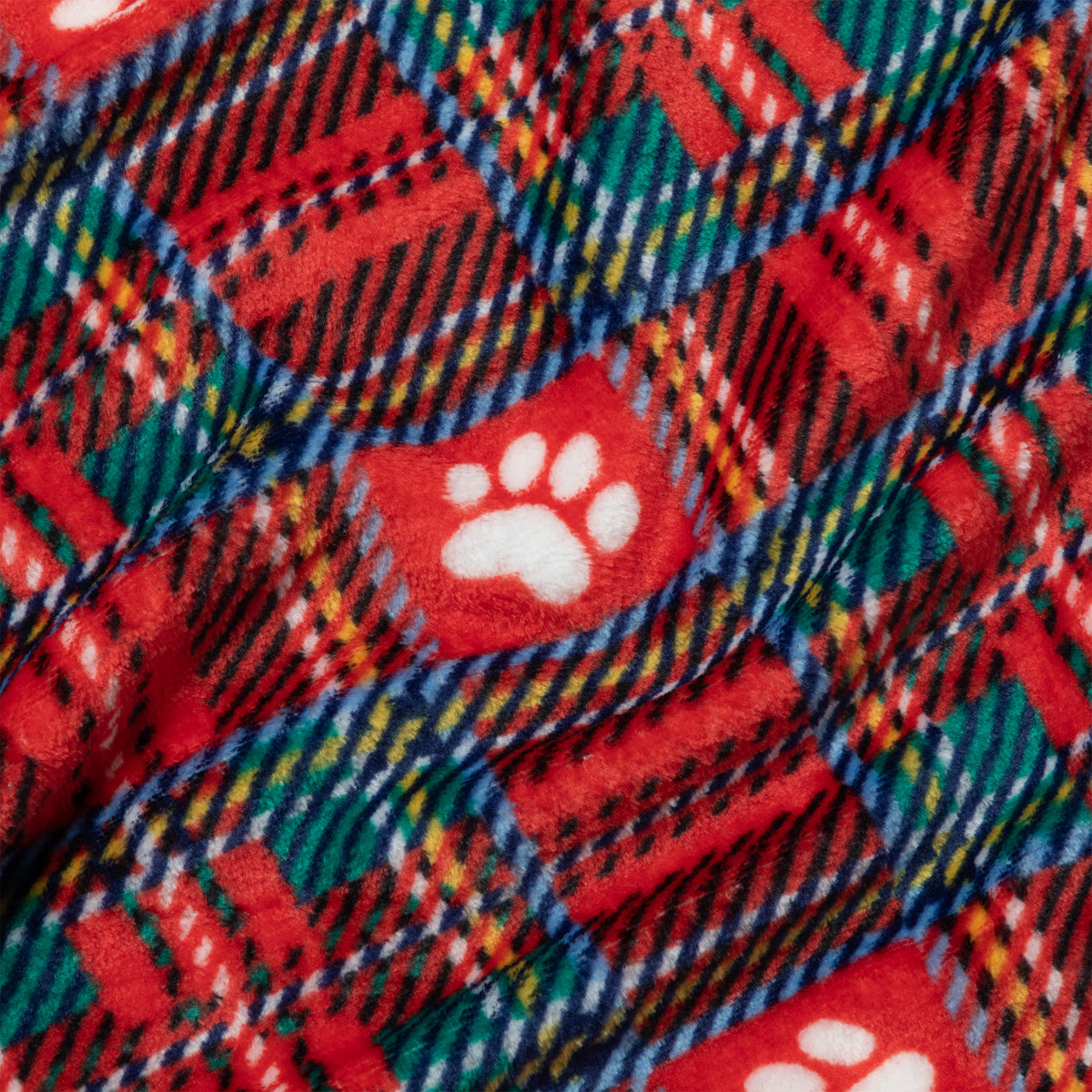 A close-up of a red holiday-themed fleece blanket featuring a plaid pattern in green, blue, yellow, and white, with white paw print motifs.