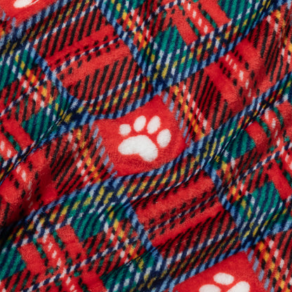A close-up of a red holiday-themed fleece blanket featuring a plaid pattern in green, blue, yellow, and white, with white paw print motifs.