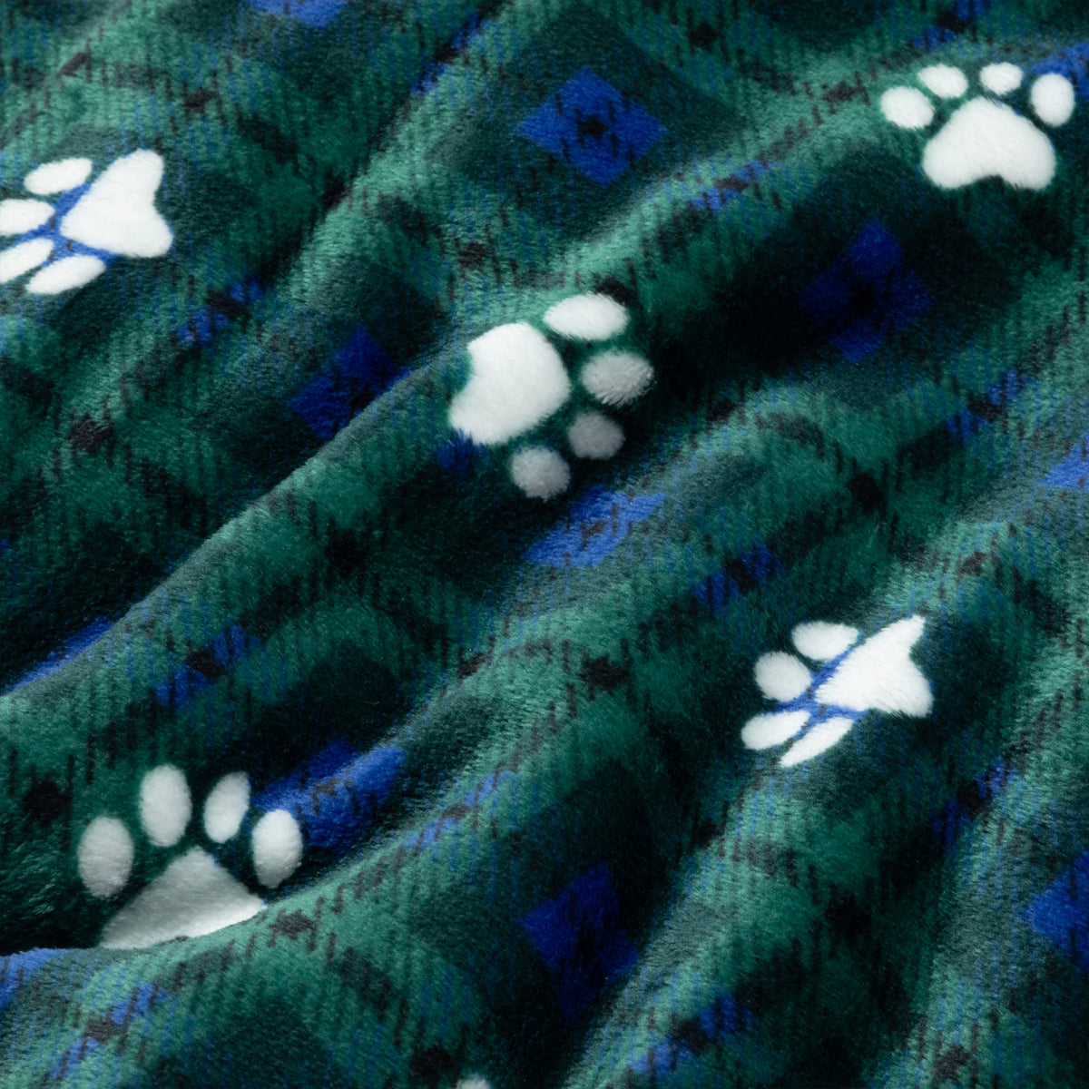 A close-up of a plush fleece blanket with a green and blue plaid pattern and white paw print motifs.