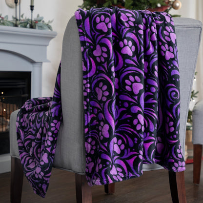 Purple and black patterned blanket draped over a chair in a living room setting.