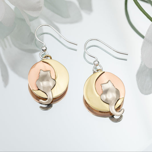Pair of cat-themed earrings with brass, copper, and silver finish on a light background