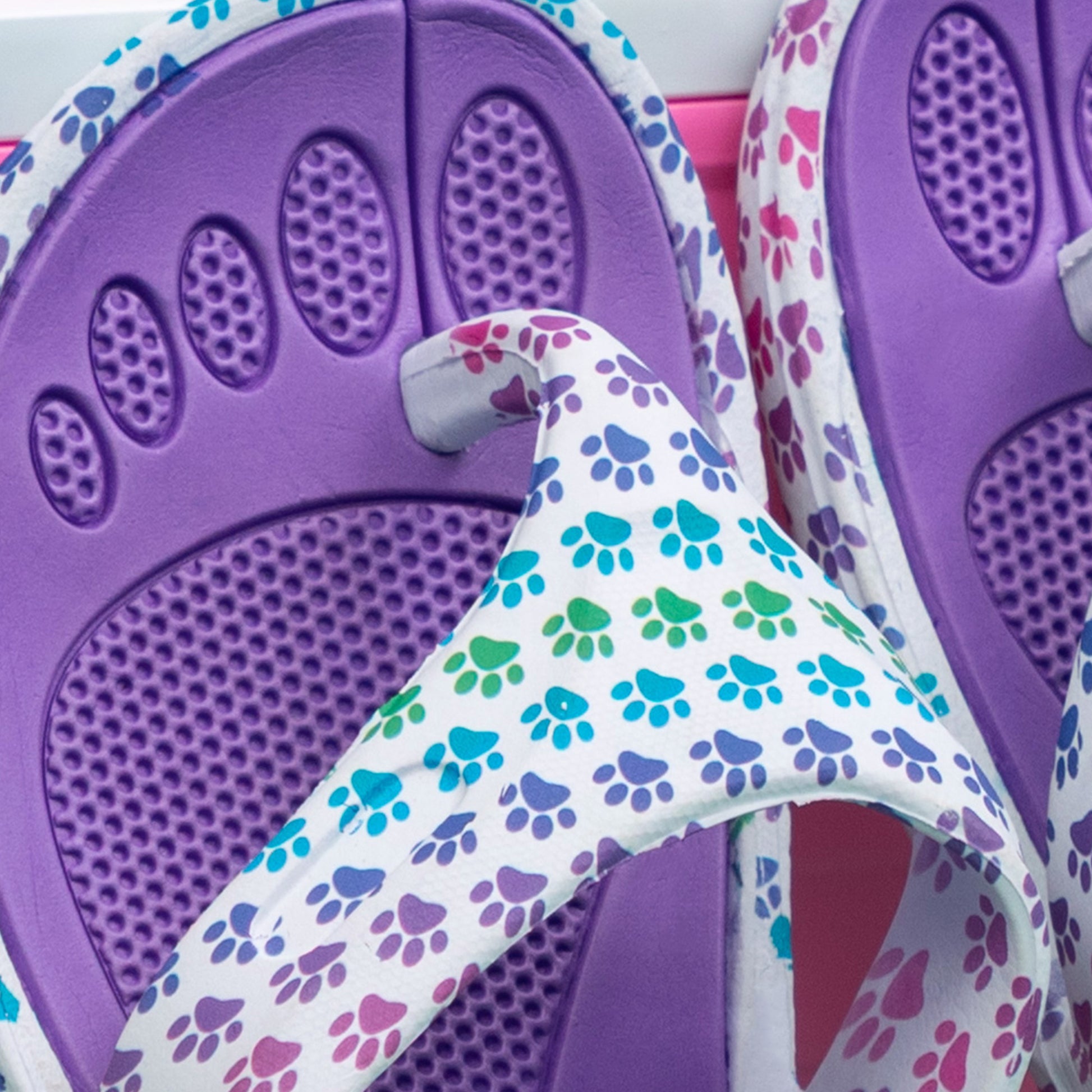 Textured insole of EVA flip flops with rainbow paw print design on top.