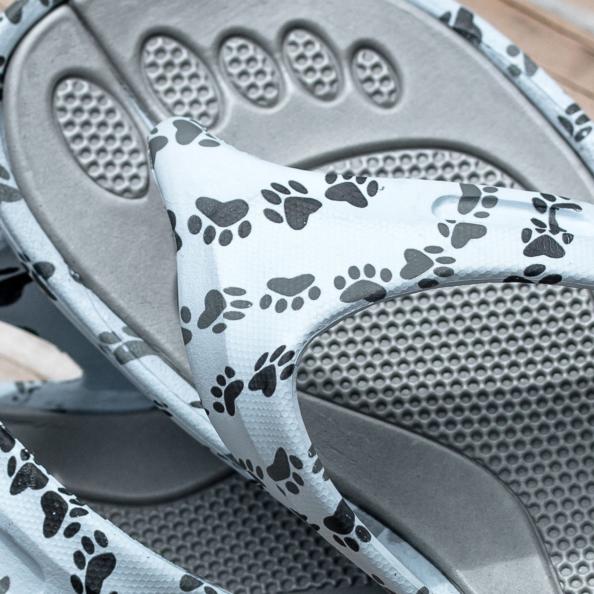 White sandals with black paw print designs on the straps, with a textured insole.