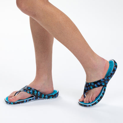 Person wearing blue and black paw print sandals on a white background.