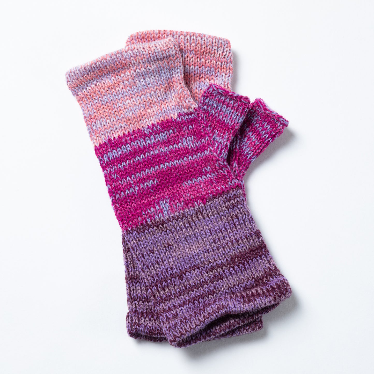 a pair of alpaca fingerless mittens in shades of pink and purple made from alpaca wool on a white background