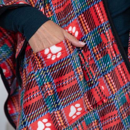 Close-up of a red plaid fleece vest with white paw print pockets, worn by a person whose hand is tucked into the pocket.