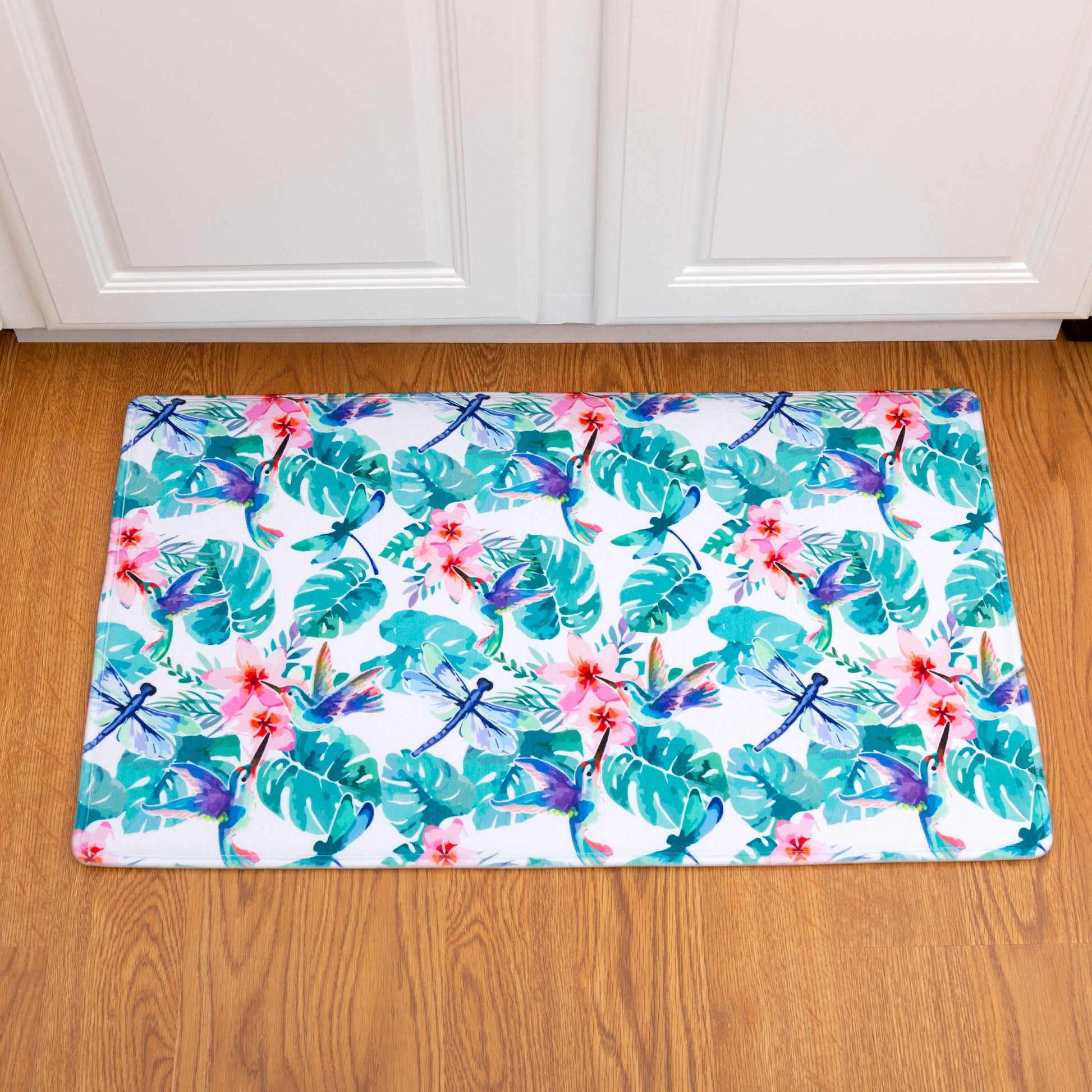 Decorative memory foam floor mat with tropical leaf and flower pattern on a wooden floor.