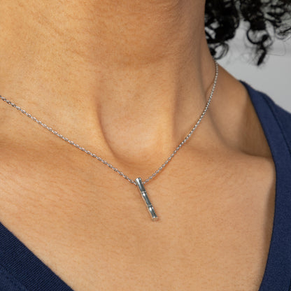 Silver necklace with a pendant on a person wearing a blue top.