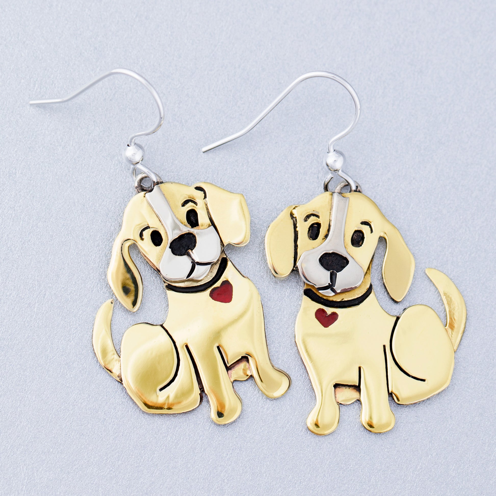 Brass dog-shaped earrings on a light gray background