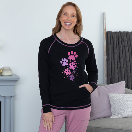 Woman wearing a black thermal top with pink paw prints in a living room setting