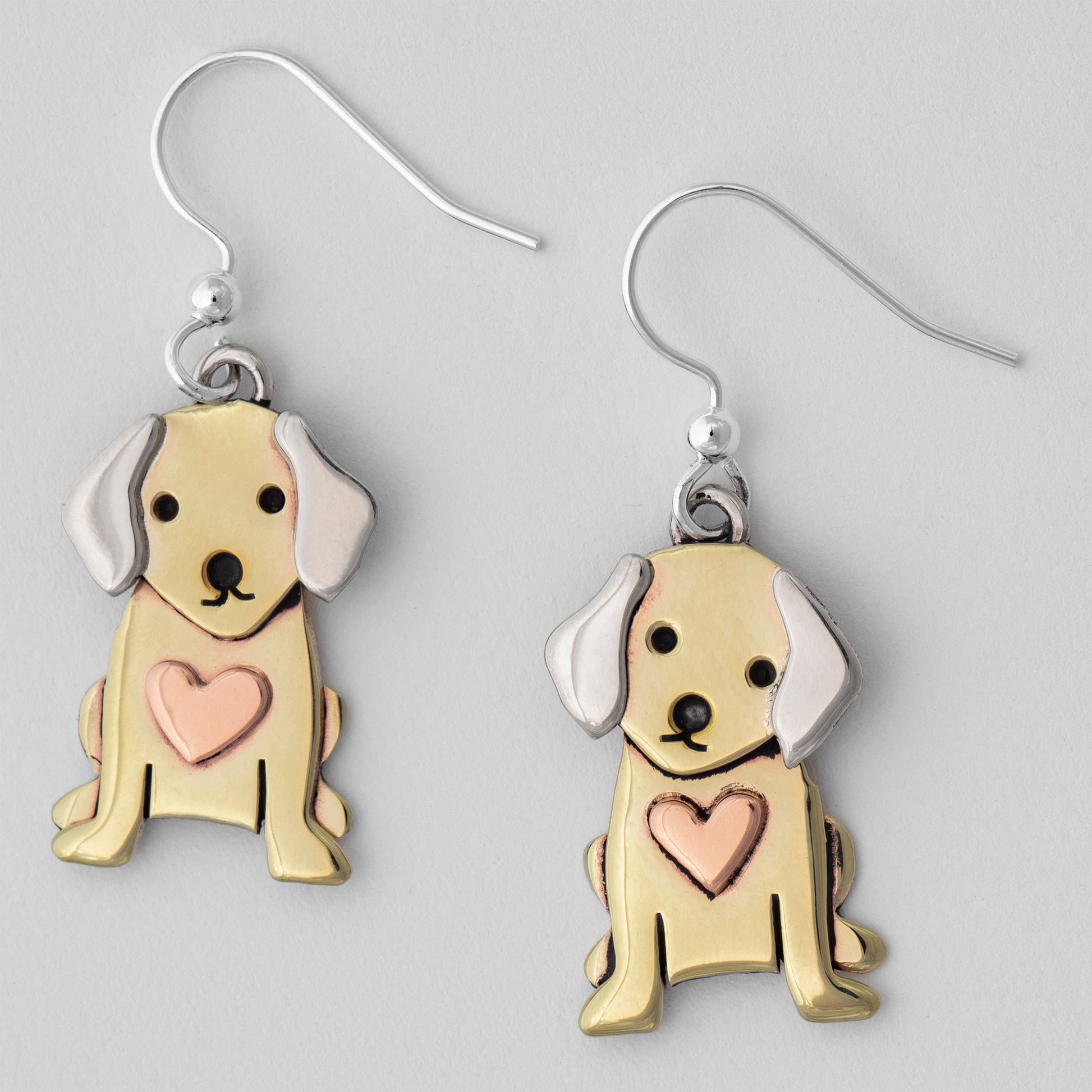 Dog-shaped earrings with copper hearts on a gray background