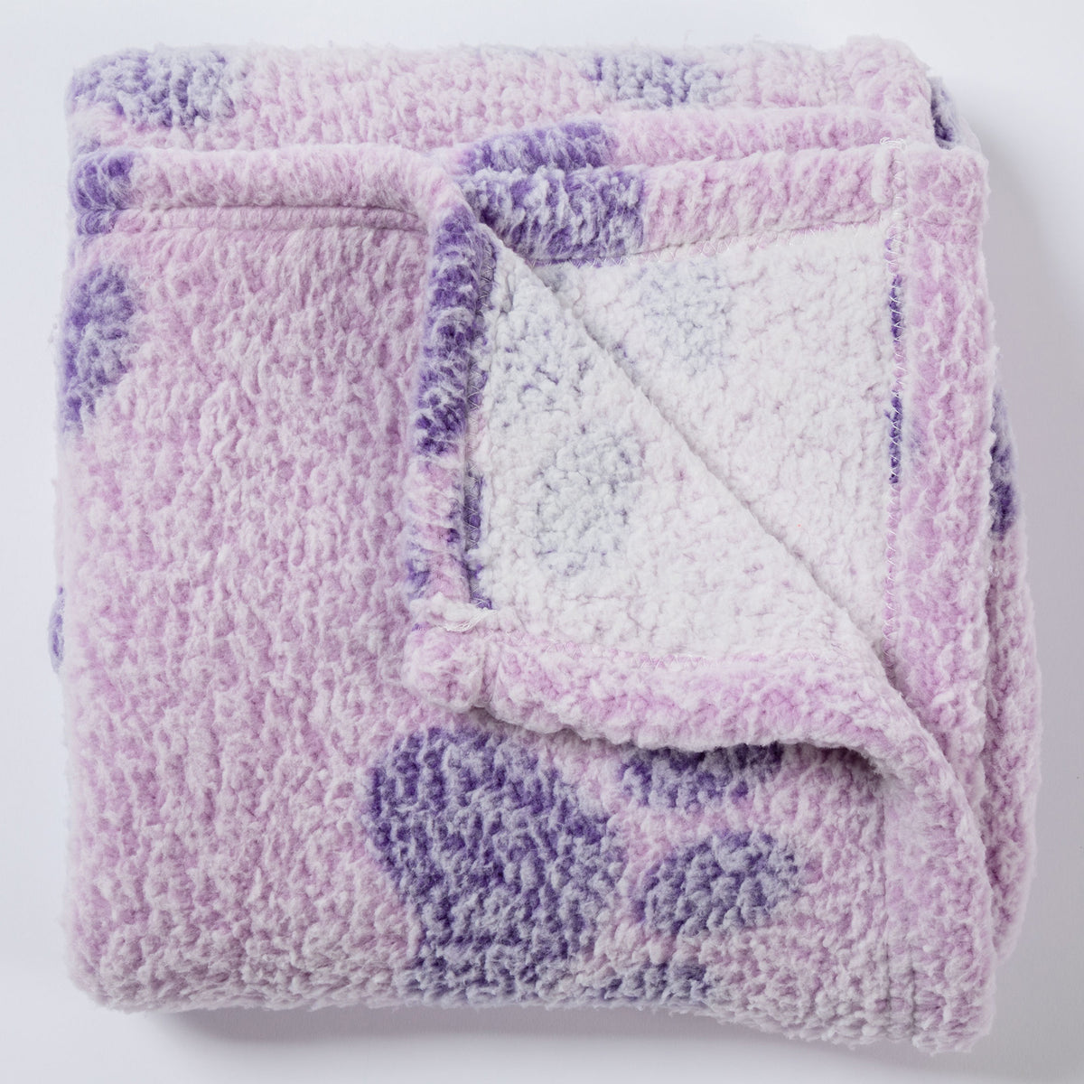 A folded plush sherpa blanket in lavender and purple with a white sherpa lining, shown on a clean white background.
