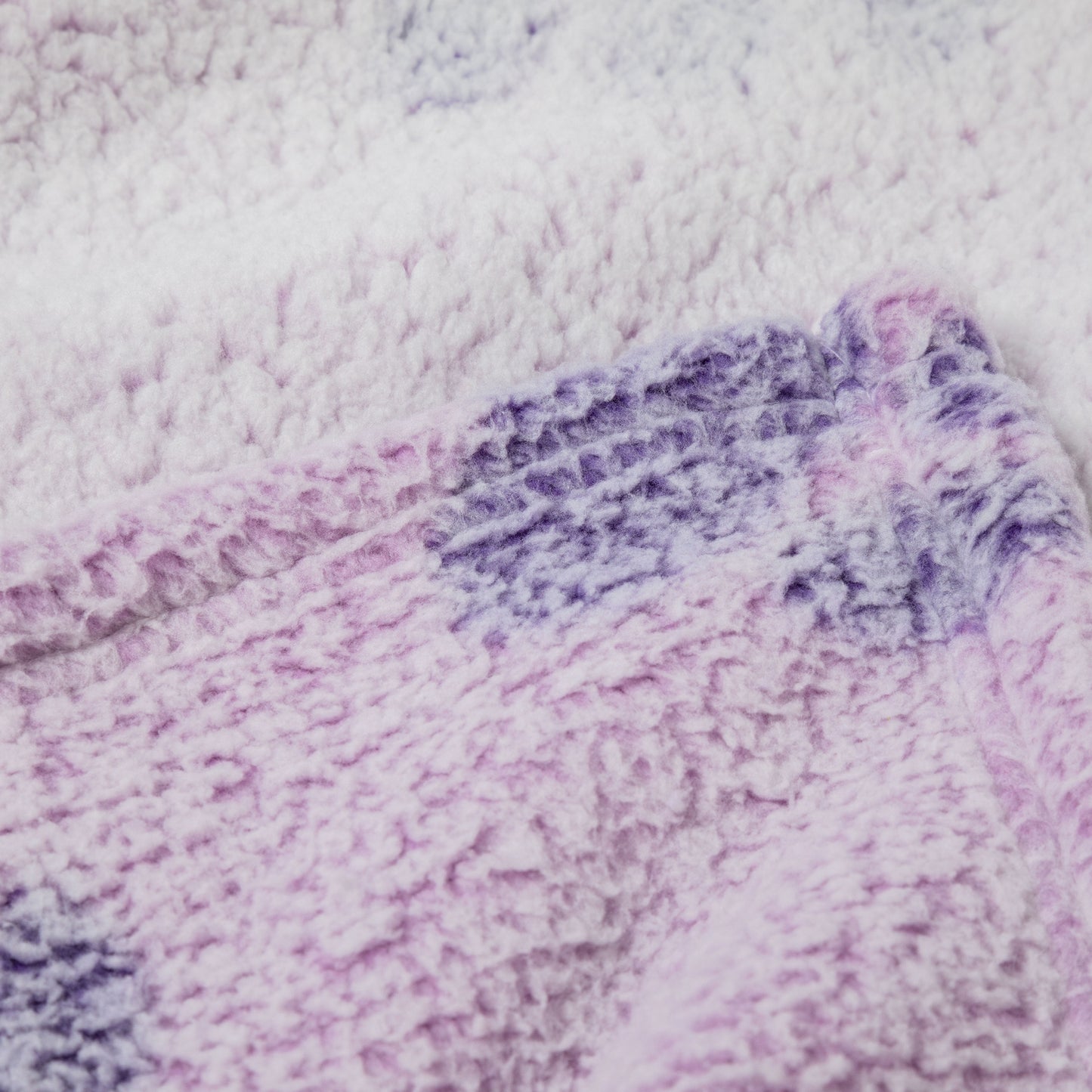 Close-up of a plush, textured blanket in a soft pastel mix of lavender, light purple, and white.