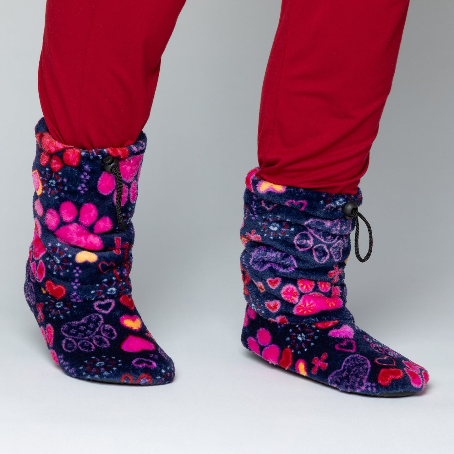 Navy blue fleece slipper booties with bright pink hearts and paw prints all over, against a white background.