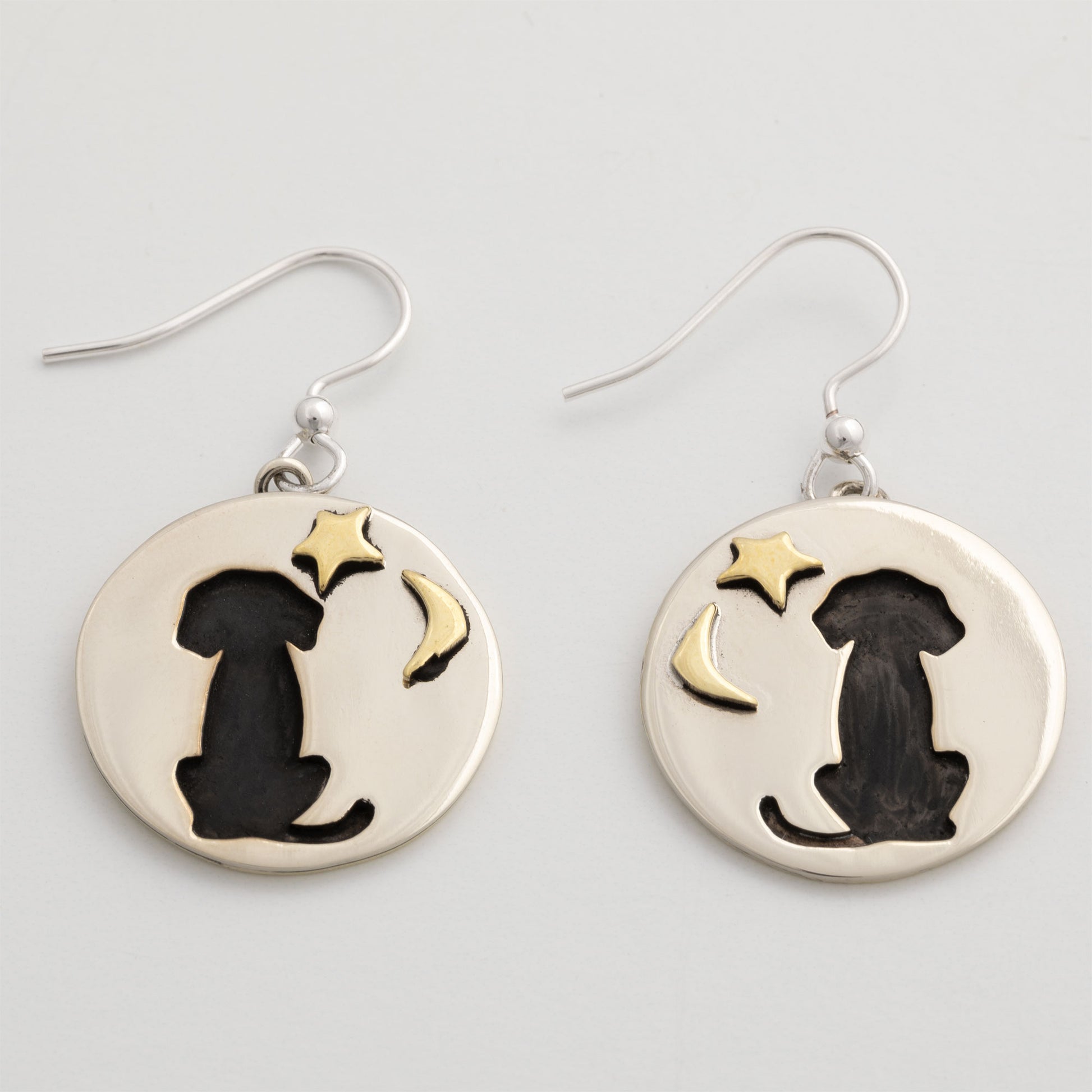 Silver earrings with black silhouette of a dog and gold star and moon on a white background