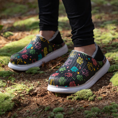 Colorful floral-patterned slipper shoes on a person standing on a natural ground.