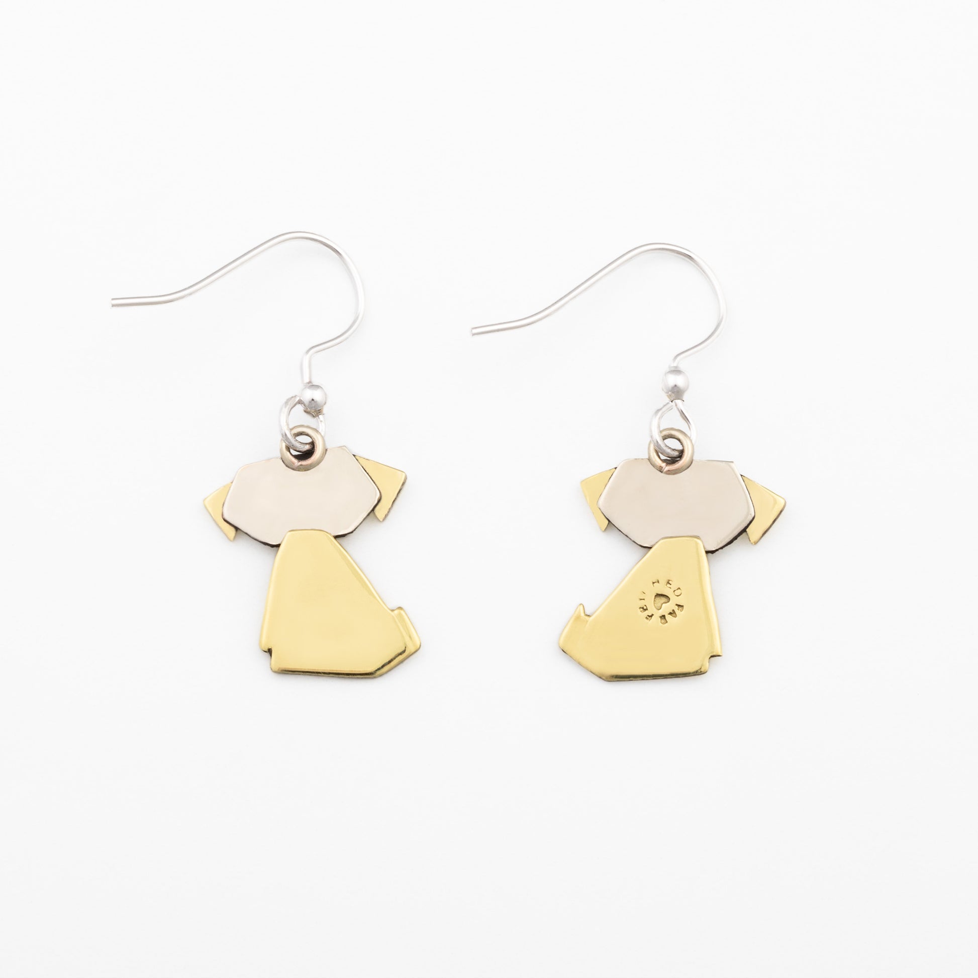 The backs of a pair of earrings with brass and silver dog-shaped pendants on a white background