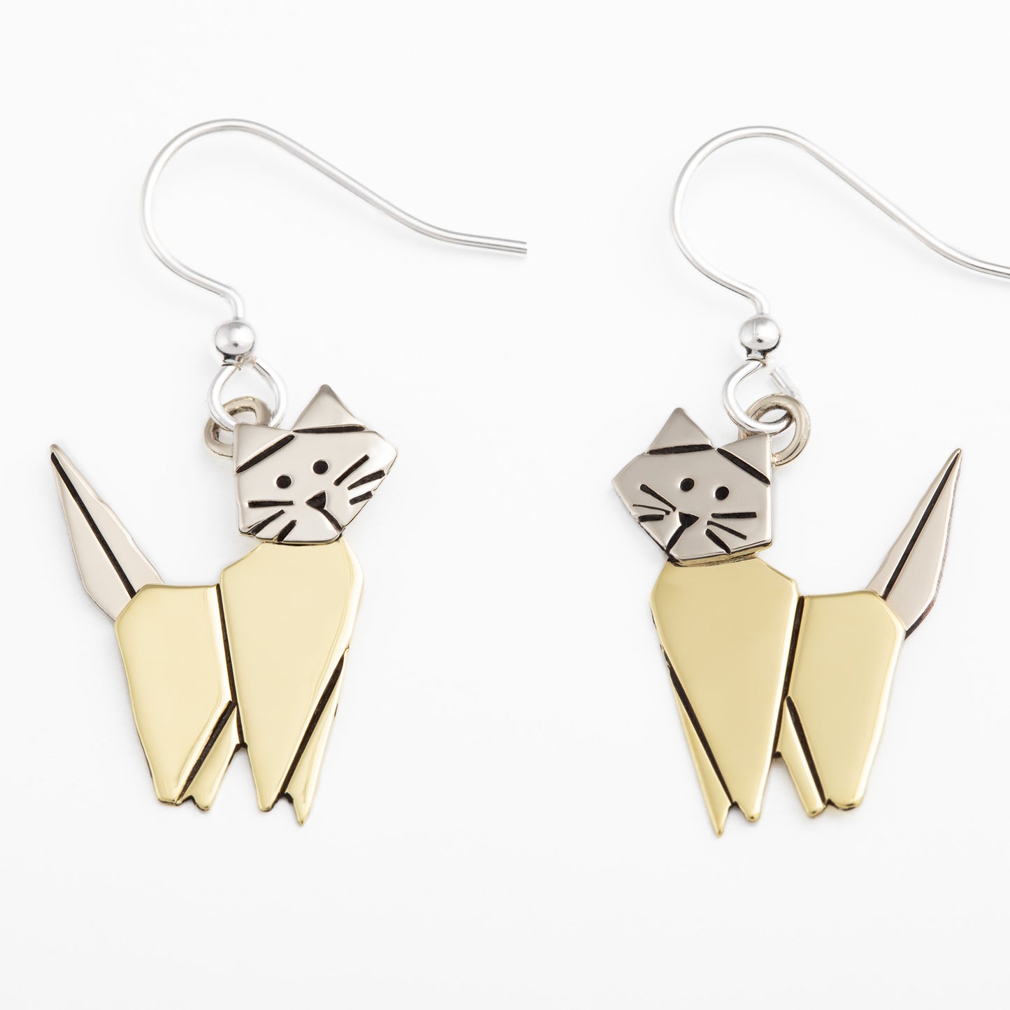 Pair of origami style cat-shaped earrings with brass and silver design on a white background