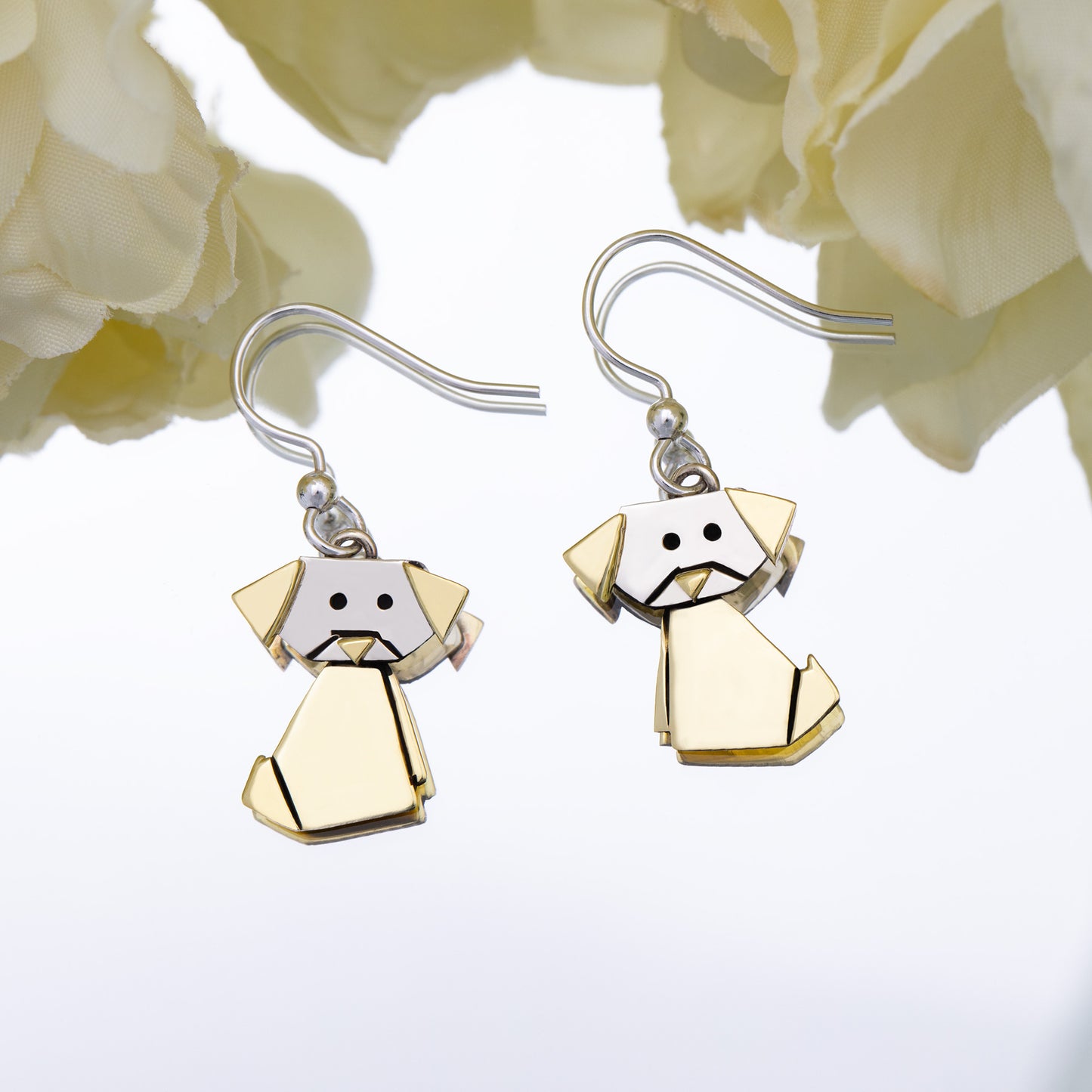 Dog-shaped origami style earrings on a white background with flowers