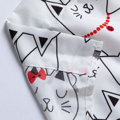 Close-up of a white fabric product printed with black cat face outlines and red bow tie and necklace details, showing the fabric texture and stitching.