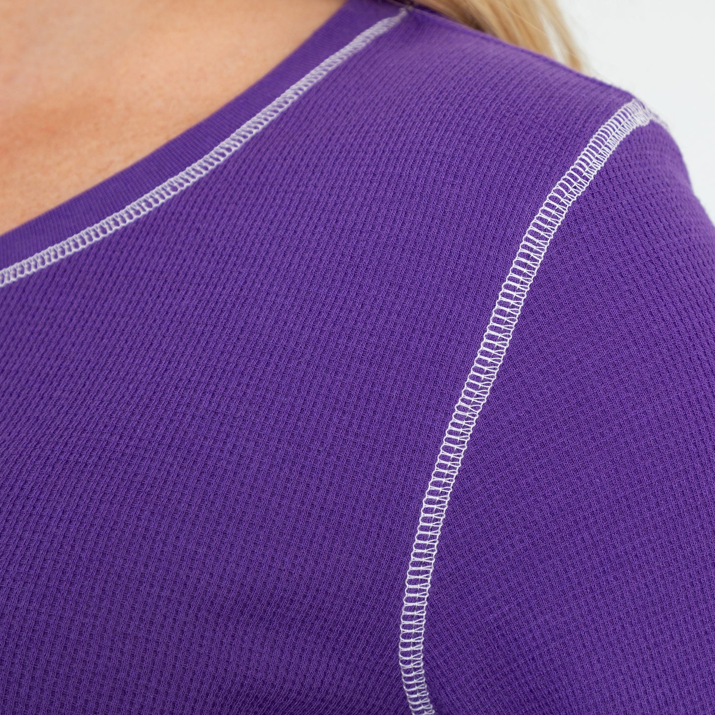 Close up of purple thermal long sleeve tee with white contrast stitching on the neck and shoulder.