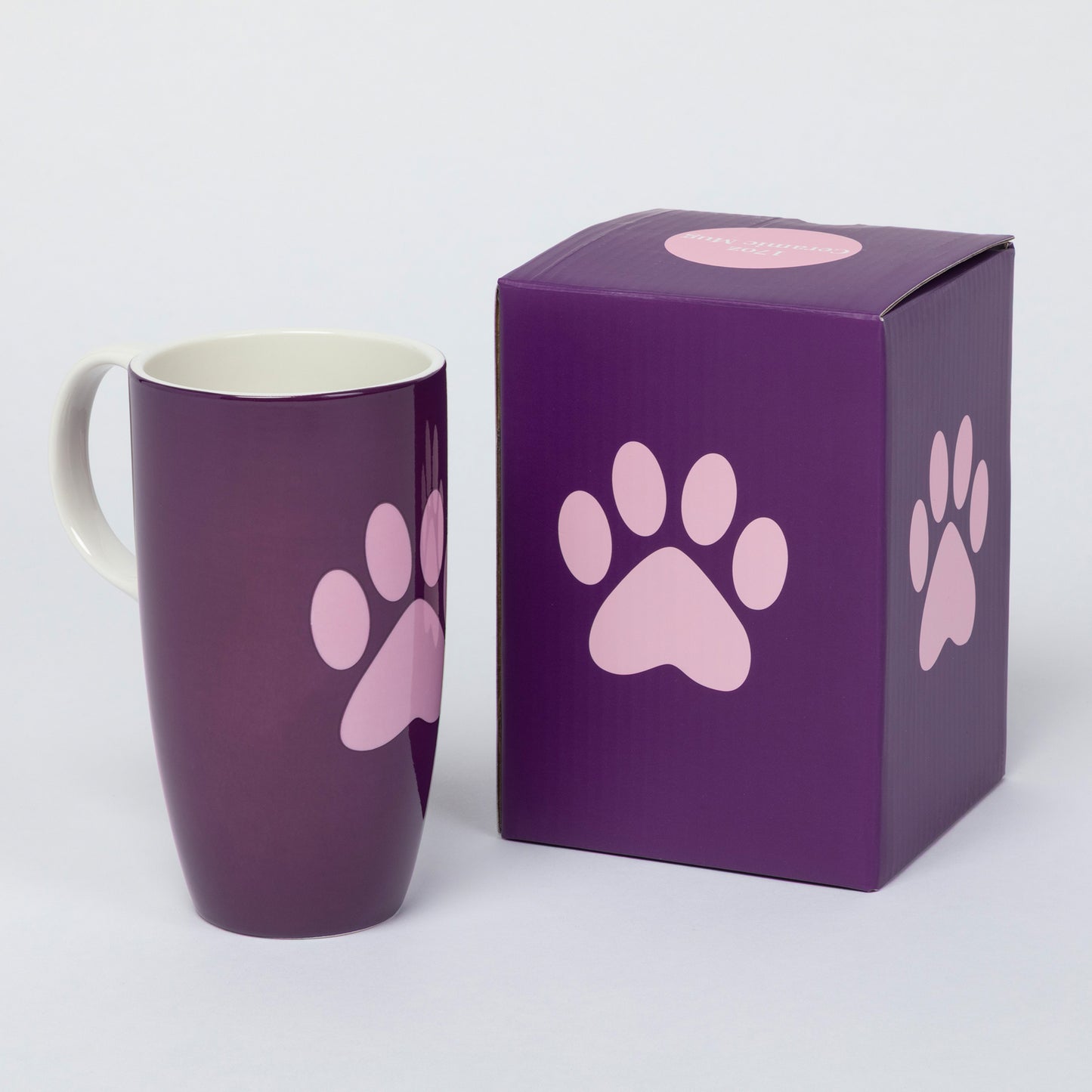 A dark purple ceramic mug with a light pink paw print design next to its matching purple and pink gift box, set against a plain light gray background.