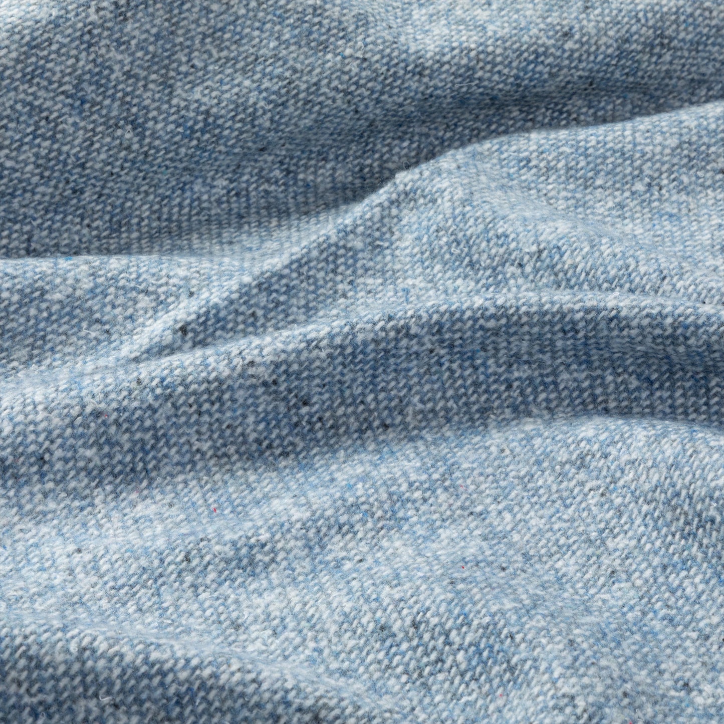 Light blue textured fabric with subtle woven patterns and gentle wrinkles.